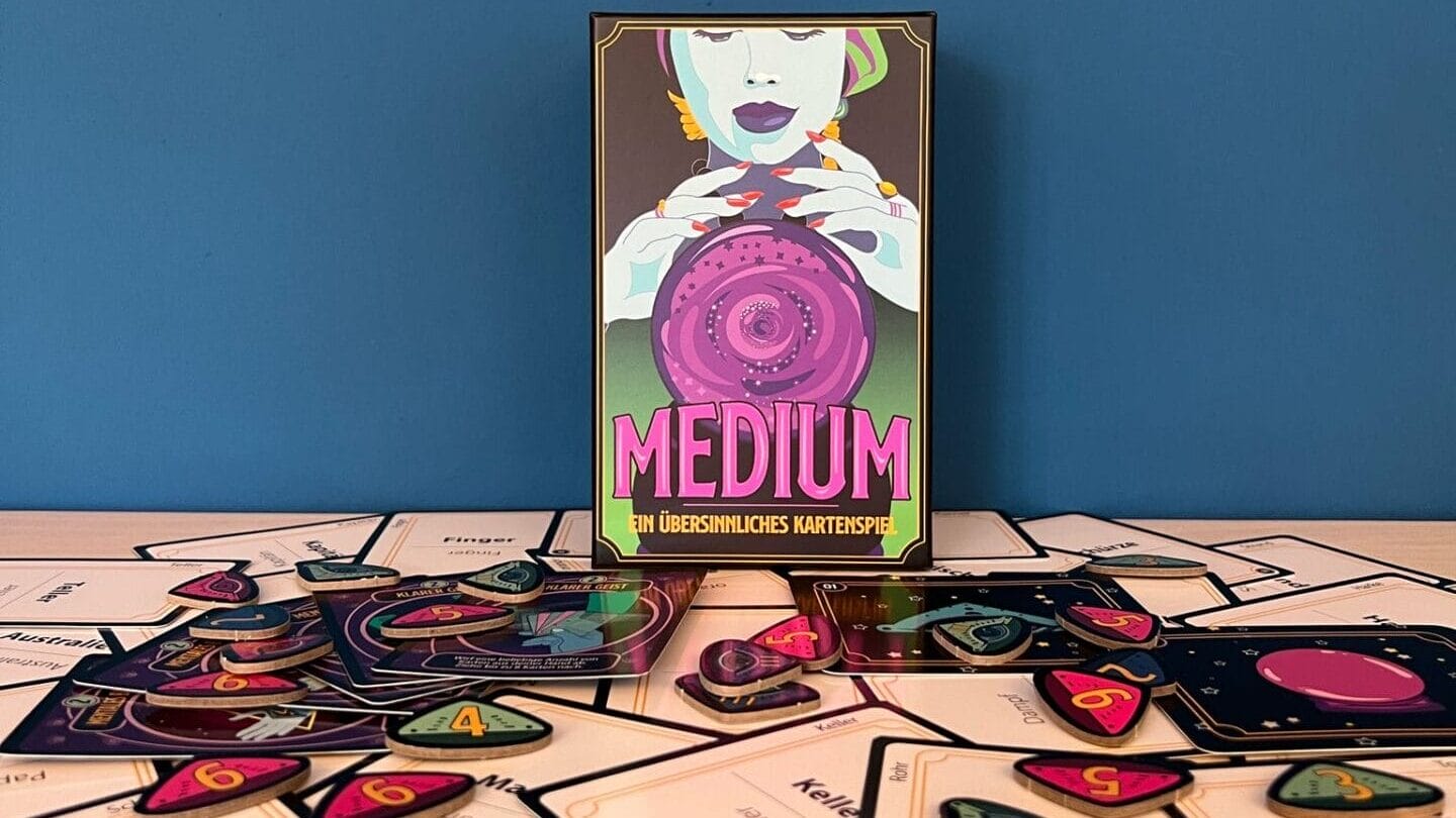 Das Brettspiel "Medium" steht auf einer Platte mit seinen Bestandteilen davor ausgebreitet.